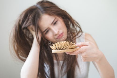 אישה מודאגת מנשירת שיער ודלילות
