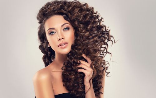 אישה עם שיער מתולתל מטופח לאחר שימוש בגלייז לשיער מתולתל